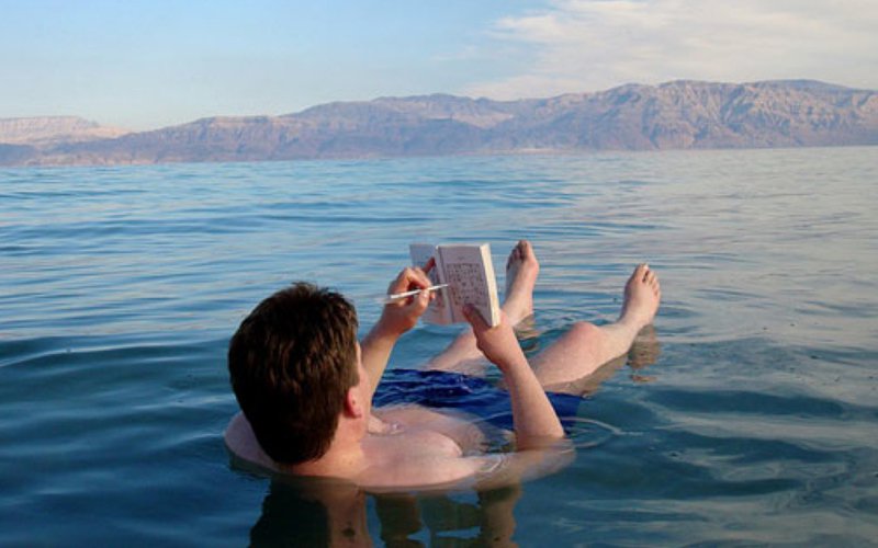 man-reading-book-while-floating-in-dead-sea