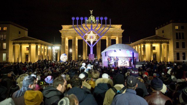 People stand in front of a giant menorah in front of the Brandenburg Gate in Berlin on December 6, 2015. (Jorg Carstensen/DPA/AFP)