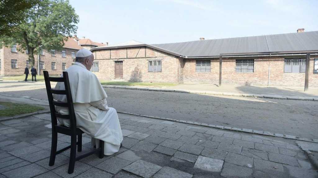 Francisco sentado frente a un barracón durante su visita al campo de concentración nazi de Auschwitz (EFE)