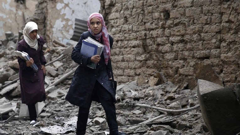 Syrian young women carry books as they walk amid the rubble of destroyed buildings following a reported air strike by Syrian government forces in the rebel-held area of Douma, east of the capital Damascus, on October 29, 2015. (Sameer al-Doumy/AFP)
