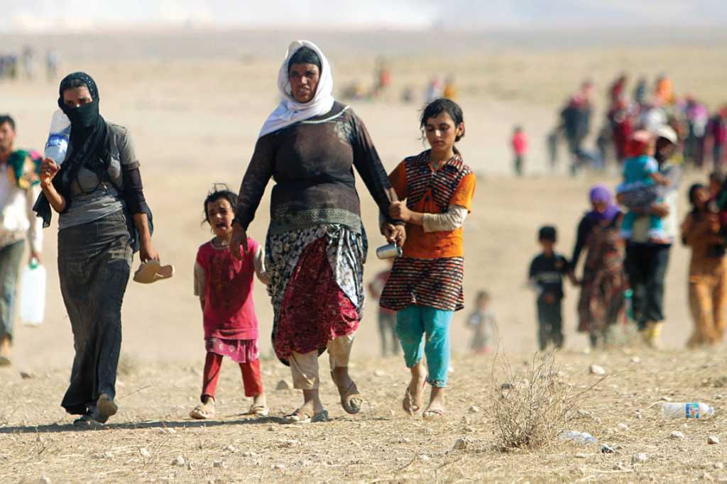 Displaced people from the minority Yazidi sect, fleeing violence from forces loyal to ISIS in the town of Sinjar, walk toward the Syrian border on Aug. 11, 2014. Photo by Rodi Said/ Reuters