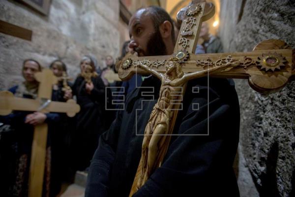 Un fiel carga con una cruz durante una oración en la Iglesia del Santo Sepulcro tras finalizar una procesión de Viernes Santo por la Vía Dolorosa en el casco viejo de Jerusalén (Israel) hoy, 14 de abril de 2017. EFE