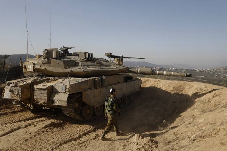 Una foto tomada el 16 de noviembre de 2017 muestra a un soldado israelí caminando al lado de un tanque en una posición del ejército con vista al sur del Líbano en la ciudad de Metula, al norte de Israel, a lo largo de la frontera de Israel con Líbano. (AFP PHOTO / MENAHEM KAHANA)