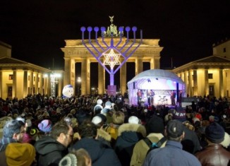 People stand in front of a giant menorah in front of the Brandenburg Gate in Berlin on December 6, 2015. (Jorg Carstensen/DPA/AFP)