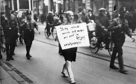 Miembros del partido nazi fuerzan a un judío a llevar un cartel en público en el año 1933.