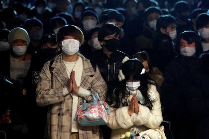 Personas con mascarilla rezan por la llegada del nuevo año. REUTERS/Issei Kato