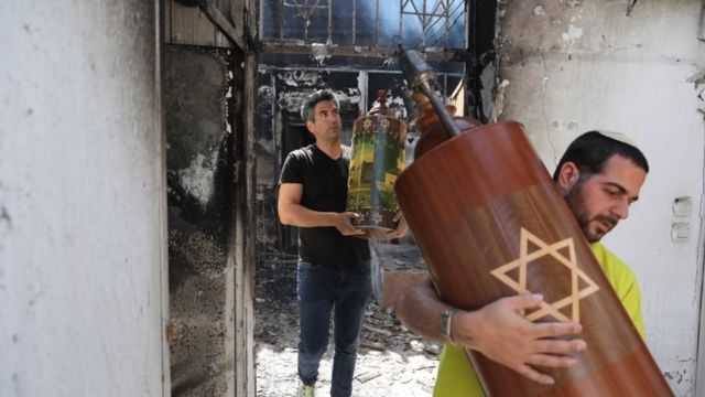 Dos hombres retiran restos de una sinagoga incendiada en Lod.