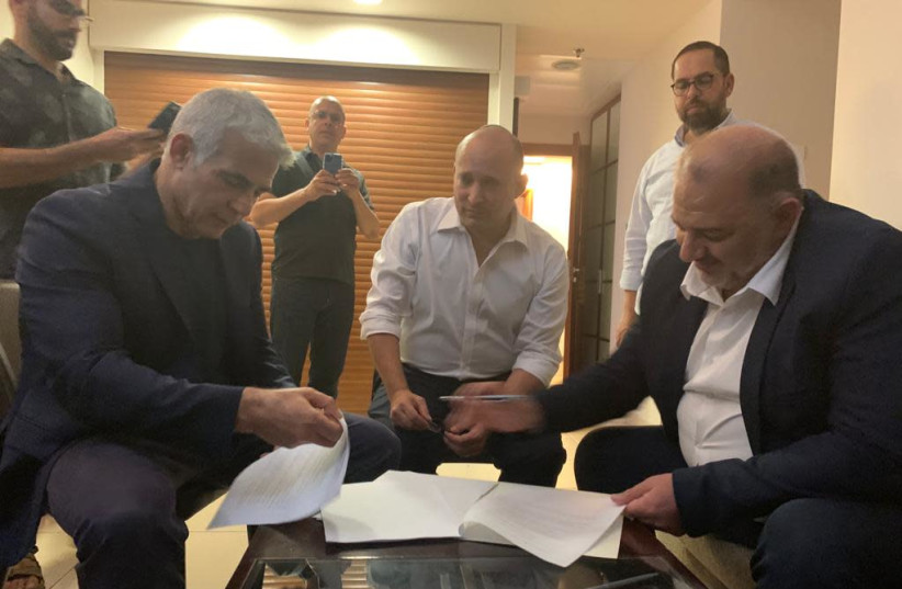 Se ve a Naftali Bennett, Yair Lapid y Mansour Abbas firmando un acuerdo de coalición. (crédito de la foto: RA'AM)