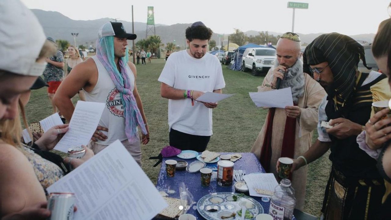 La rapera Kosha Dillz, en el centro a la derecha, vestida como Moisés, dirige mini-Seders fuera de la carpa de Shabbat en el festival de música de Coachella en Indio, California.  Dillz se refiere al evento como Matzahchella.  Foto vía Instagram/@chrism_arts