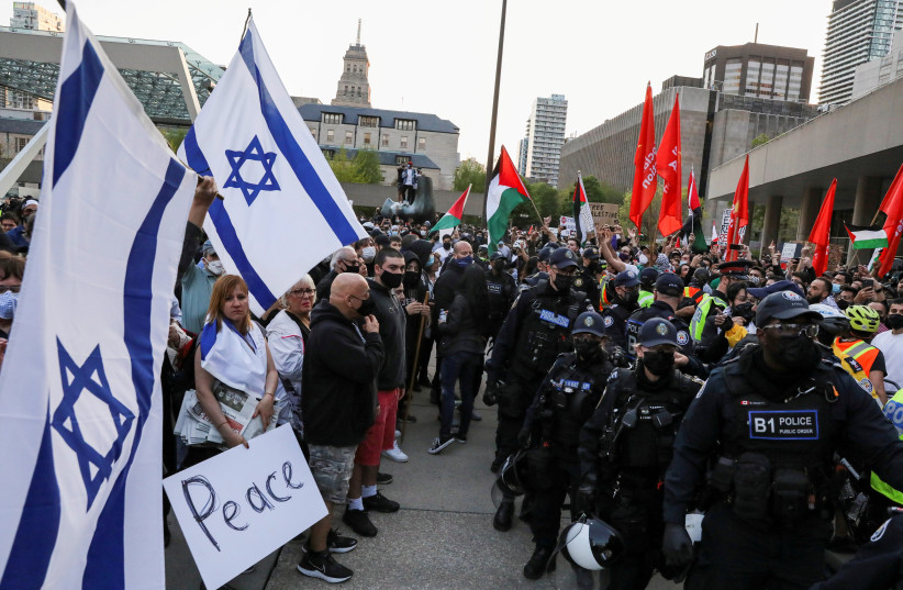 Los oficiales de policía hacen fila para separar a los manifestantes que apoyan a los palestinos de un pequeño grupo de simpatizantes de Israel frente al ayuntamiento en Toronto, Ontario, Canadá, el 15 de mayo de 2021. (Crédito: REUTERS/CHRIS HELGREN)
