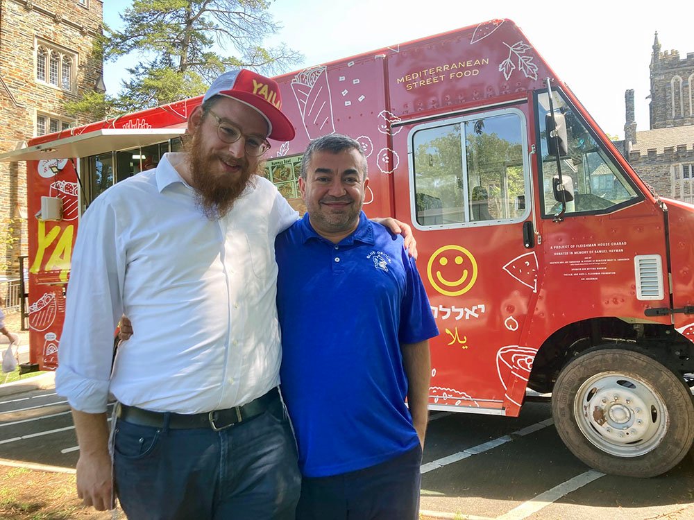 El camión de comida Yalla en la Universidad de Duke ofrece comida kosher y halal.  El camión está apoyado por el rabino Nossen Fellig de Chabad, a la izquierda, y Abdullah Antepli, profesor asociado para la práctica de las relaciones interreligiosas.  Foto de RNS por Yonat Shimron