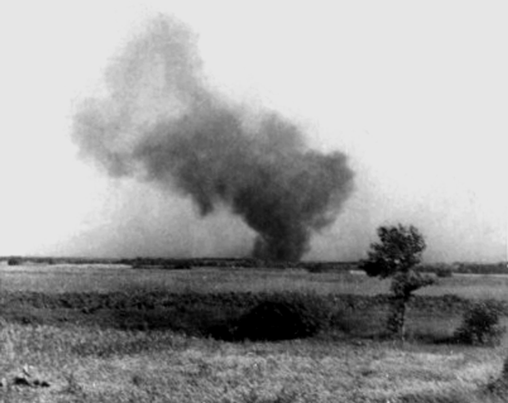 Una fotografía en blanco y negro muestra una enorme nube de humo que se eleva sobre un campo.