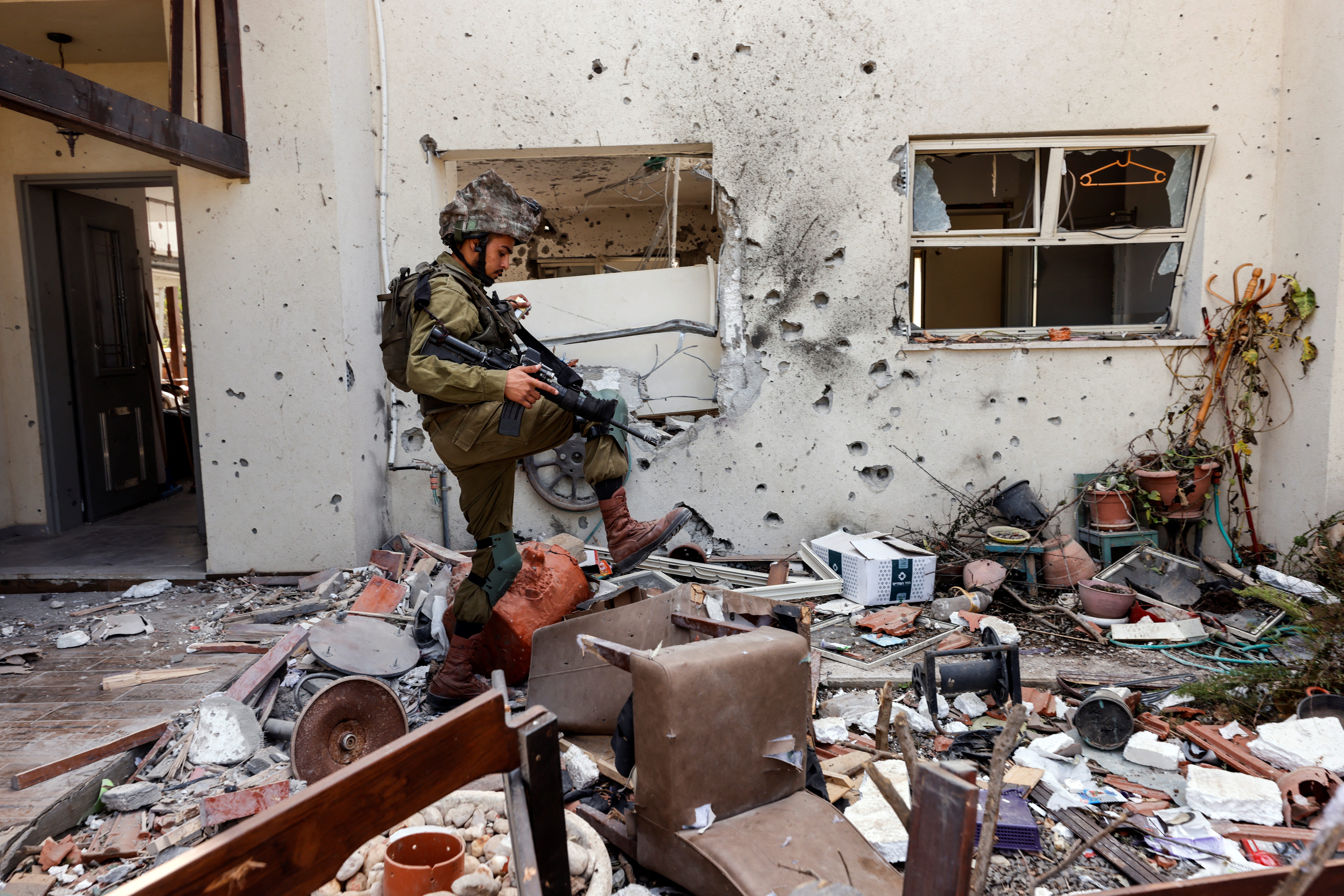 A soldier steps over debris outside a damaged home in Israel.